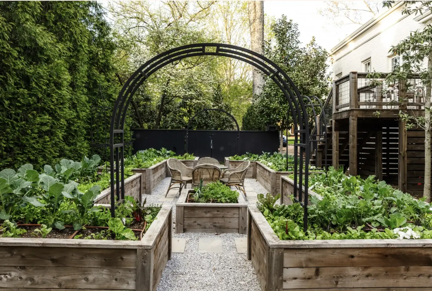 Formal raised-bed garden beneath black arched trellises